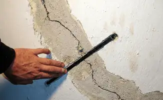 A wall with a large crack is being inspected by a professional in {city}, {state}